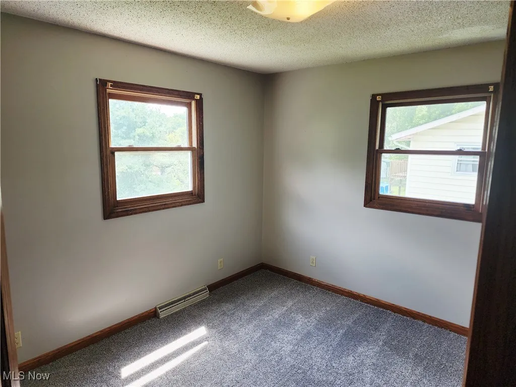 Unfurnished room with dark carpet and a textured ceiling