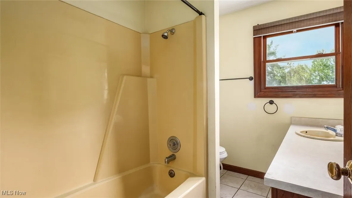 Full bath with vanity, tile patterned floors, and shower / tub combination