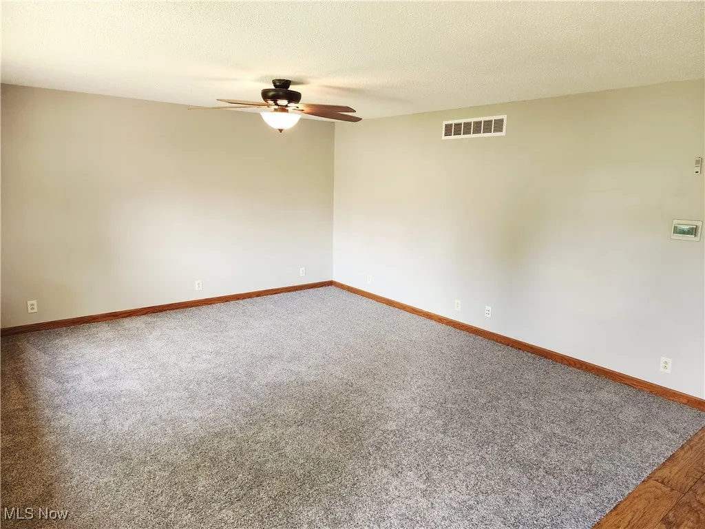 Spare room featuring a textured ceiling, carpet, and ceiling fan