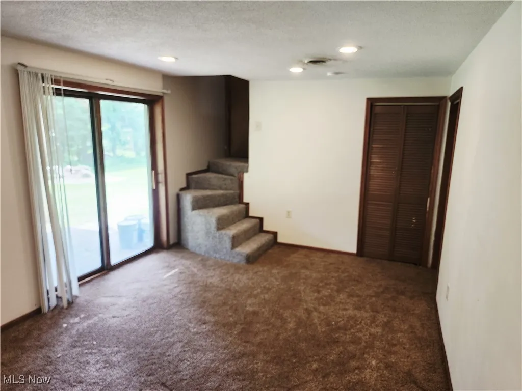 Spare room with a textured ceiling, carpet floors, stairs, and recessed lighting