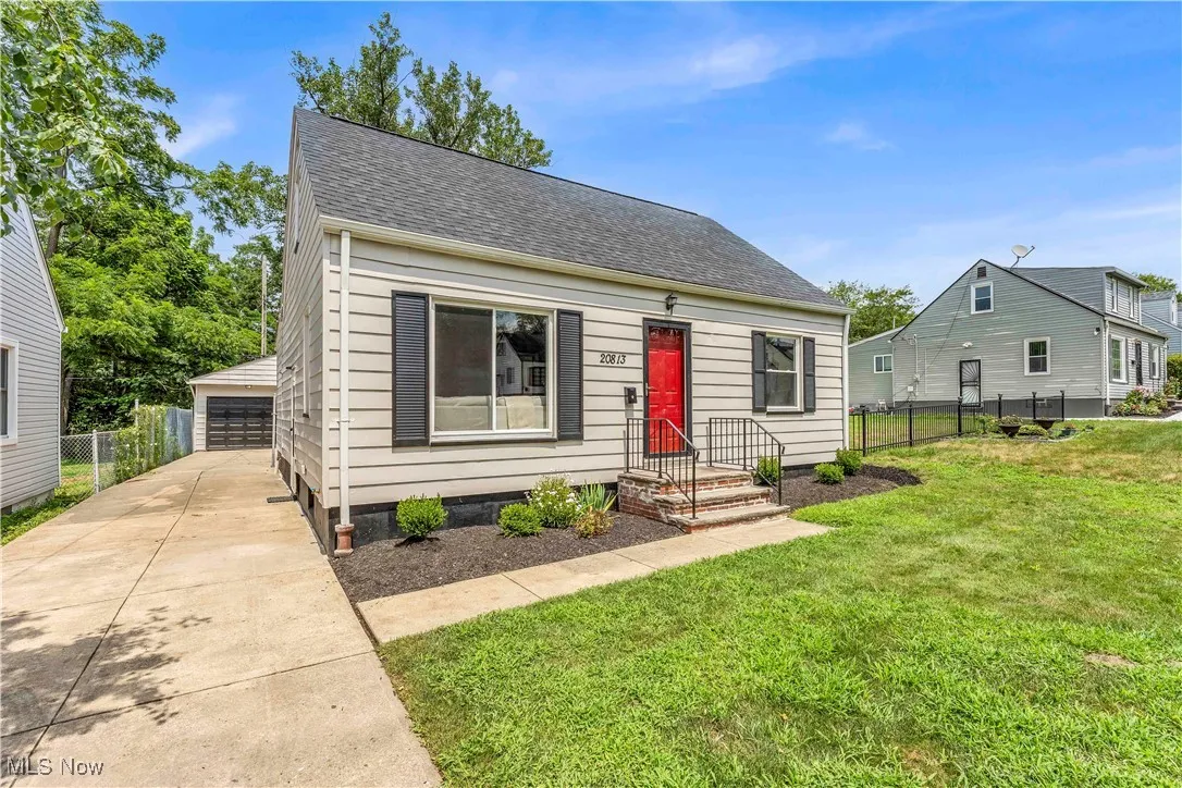 View of front of property featuring an outbuilding, a shingled roof, and a garage
