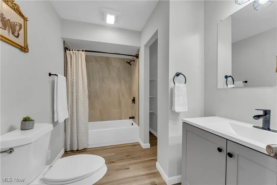 Bathroom featuring vanity, shower / bath combo with shower curtain, and wood finished floors