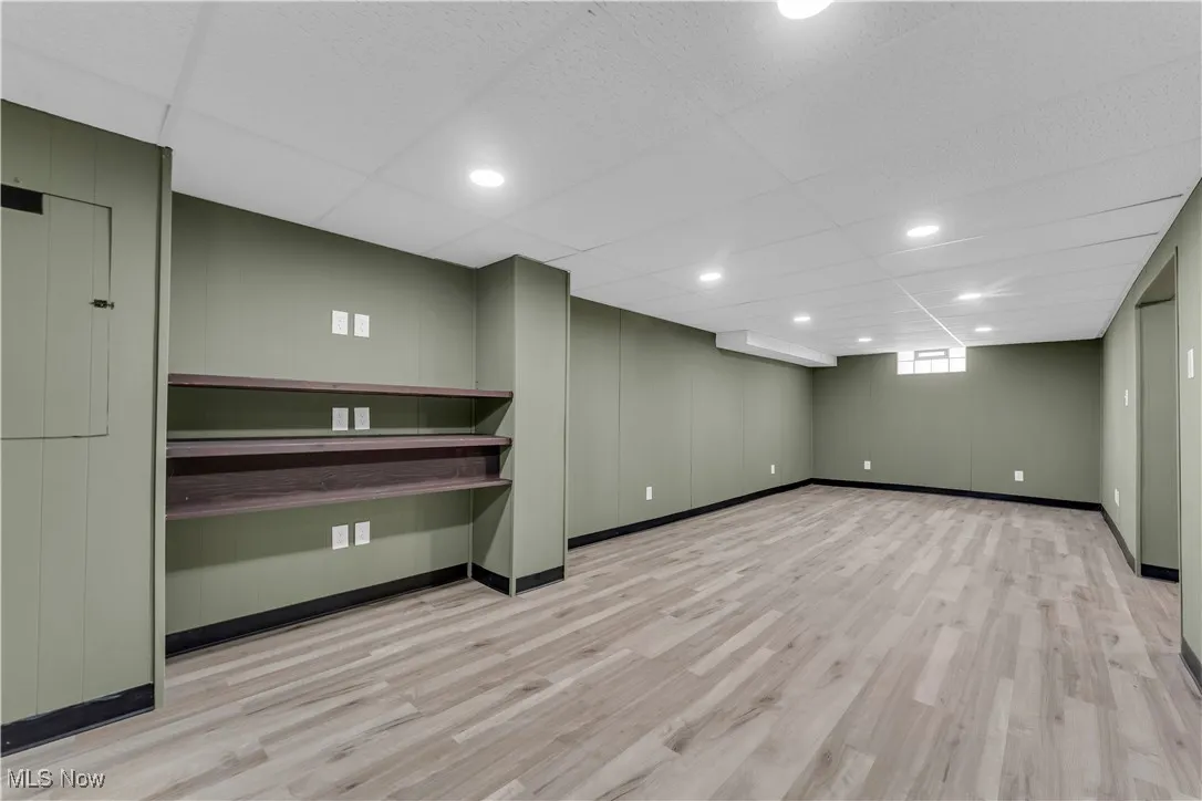 Below grade area with a drop ceiling, recessed lighting, and light wood-style floors