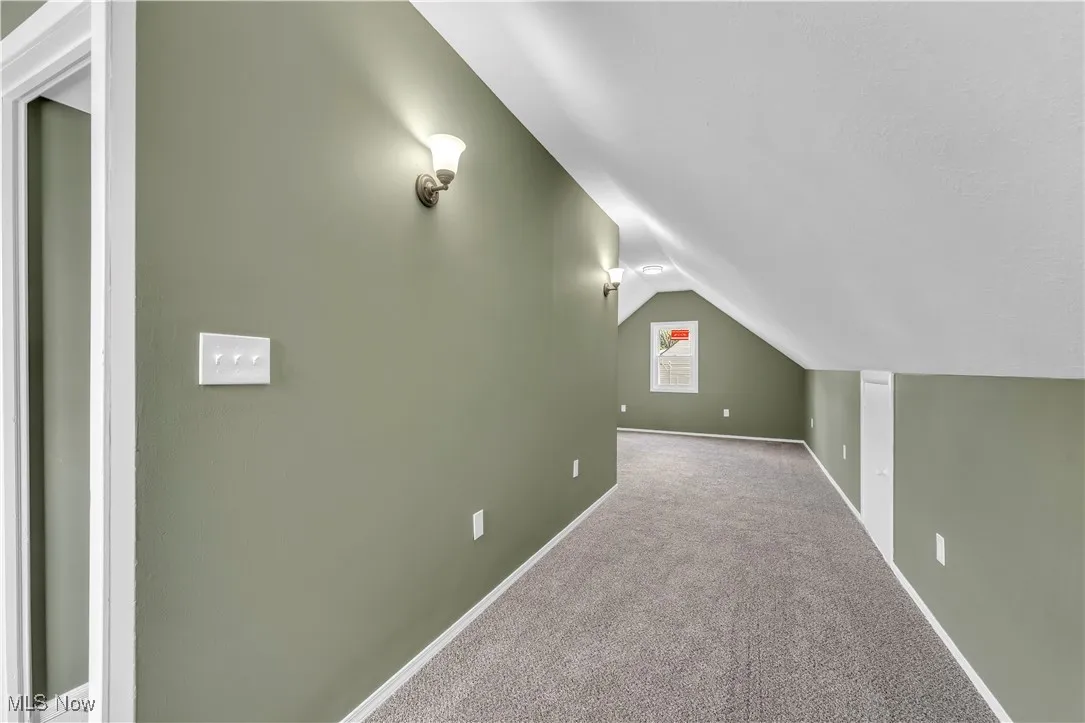 Additional living space with carpet flooring and lofted ceiling