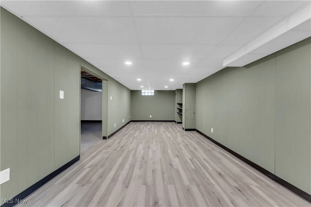 Finished basement with recessed lighting, wood walls, light wood finished floors, and a drop ceiling