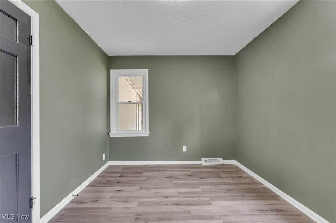 Unfurnished room with wood finished floors and baseboards