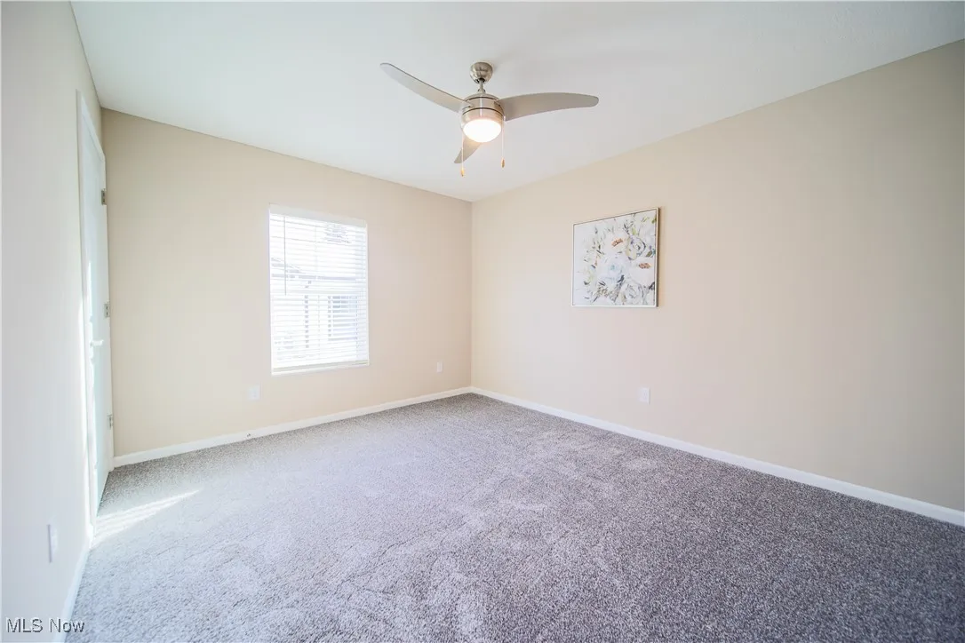 Carpeted empty room with baseboards and ceiling fan