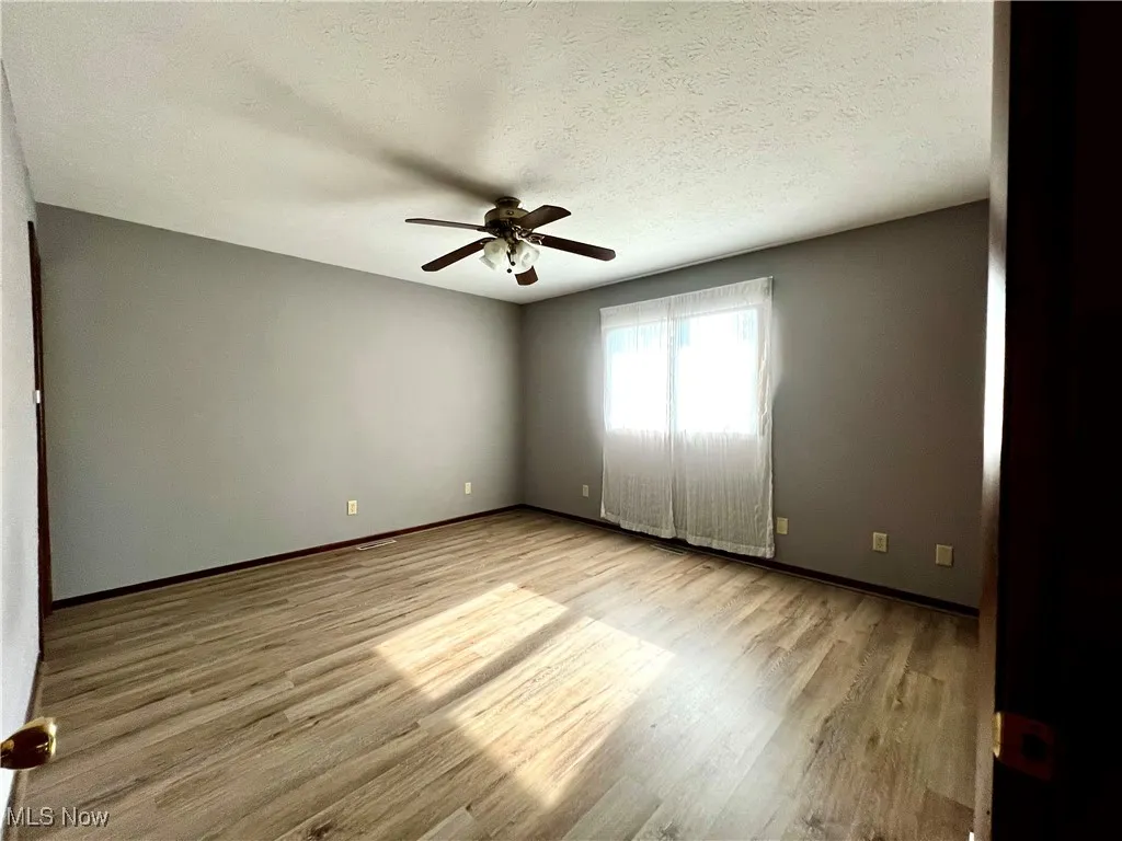 Primary bedroom with luxury vinyl flooring, a textured ceiling, and ceiling fan