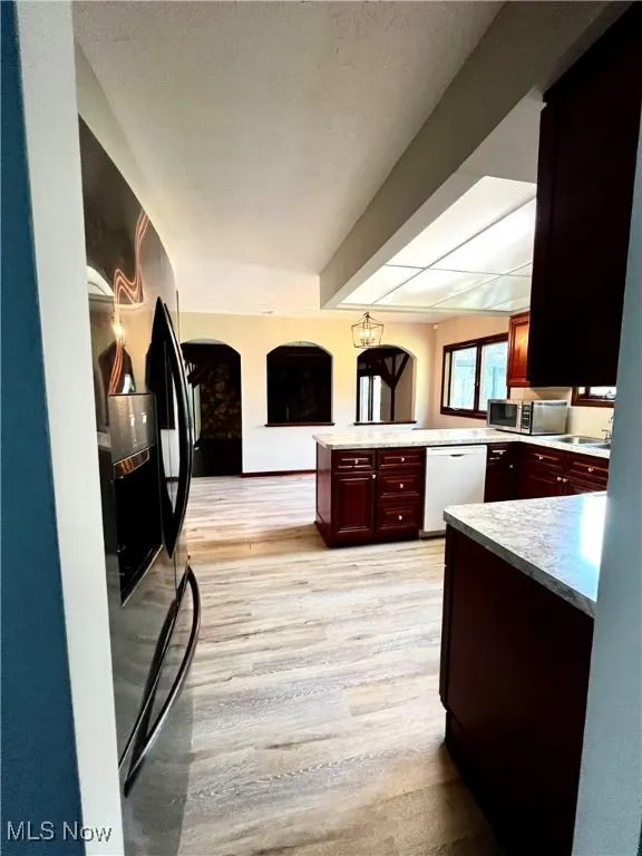 Kitchen with light countertops, light wood-type flooring, dishwasher, fridge with ice dispenser, and stainless steel microwave