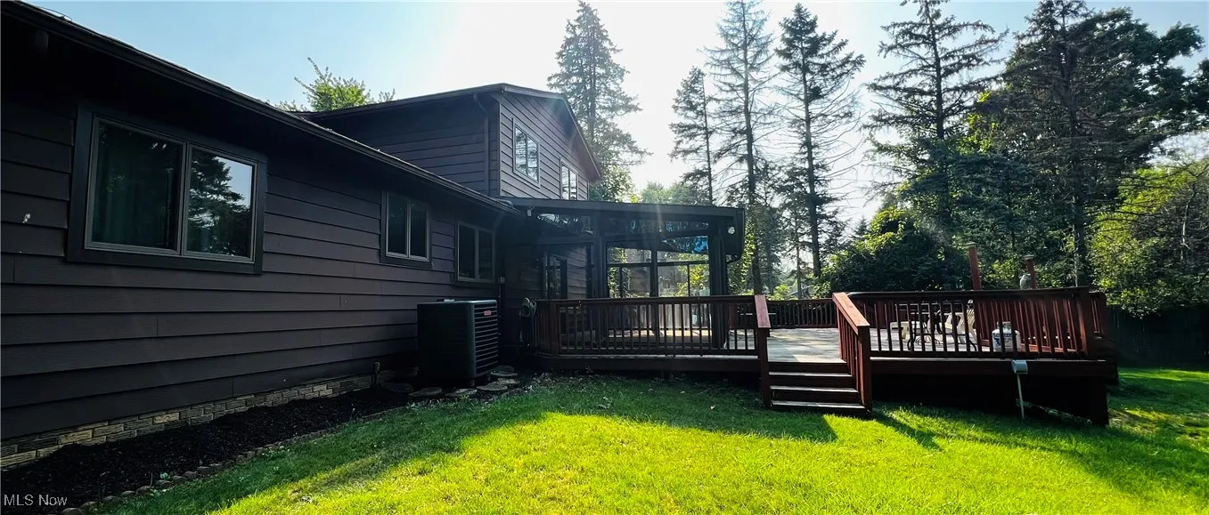 View of green lawn with a deck and a sunroom