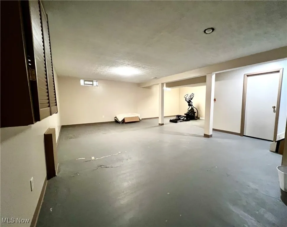 Finished basement featuring a textured ceiling and baseboards