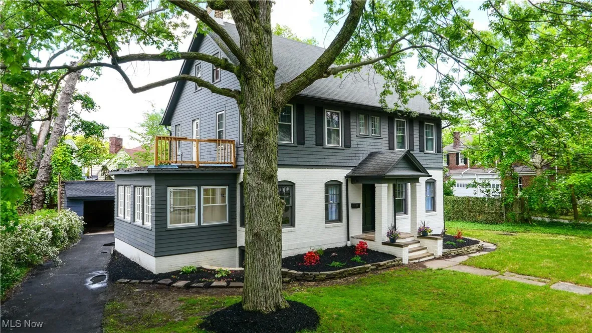 View of front of property with a shingled roof, a front lawn, and a balcony