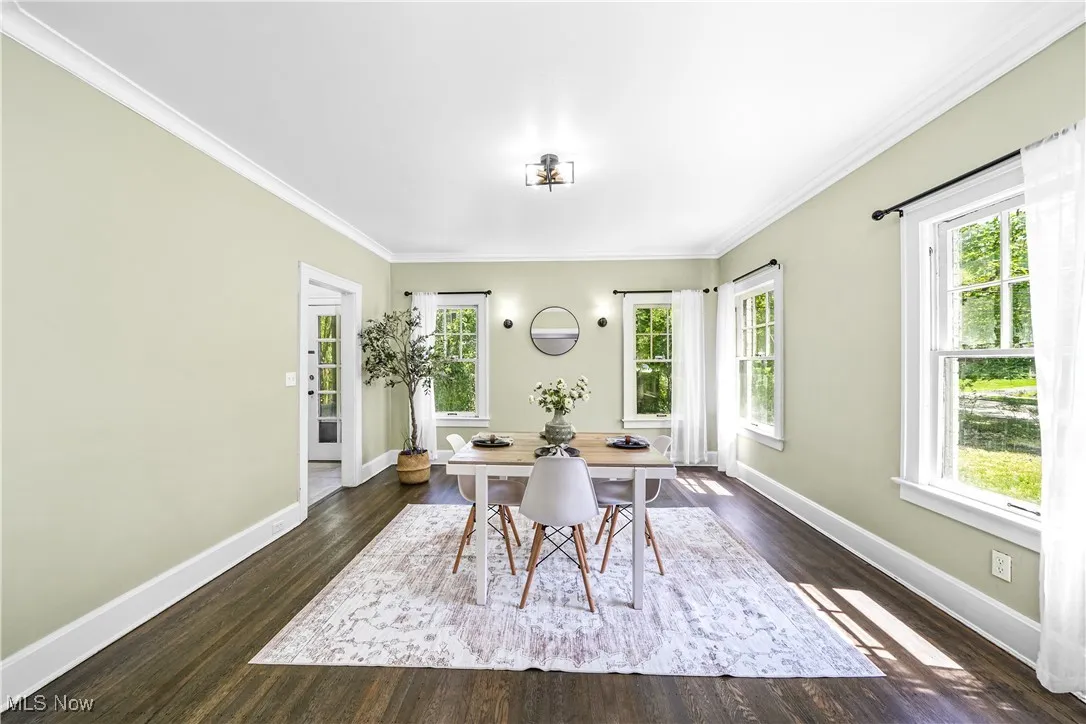 Dining space featuring plenty of natural light, crown molding, and dark wood-style flooring