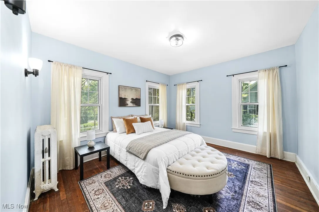 Bedroom with dark wood finished floors and radiator