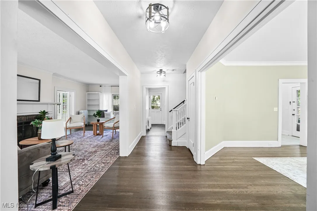 Foyer entrance with ornamental molding, healthy amount of natural light, wood finished floors, a tile fireplace, and stairway