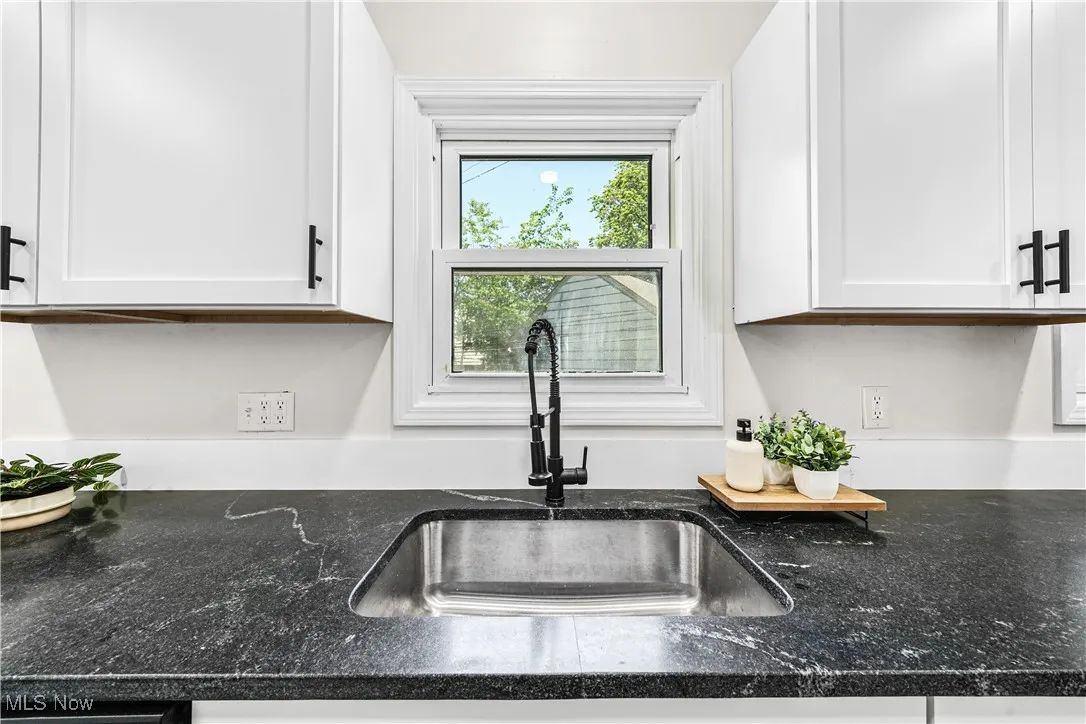 Kitchen view of white cabinetry and dark stone countertops