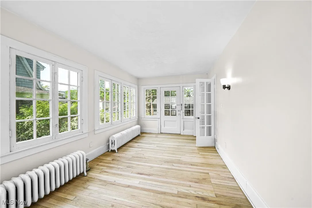 Unfurnished sunroom with radiator, french doors, and hardwood / wood-style flooring