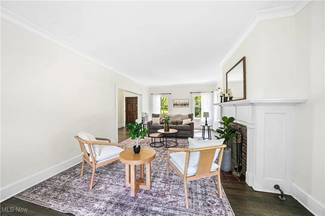 Living area with ornamental molding, a fireplace with flush hearth, and dark wood-style floors