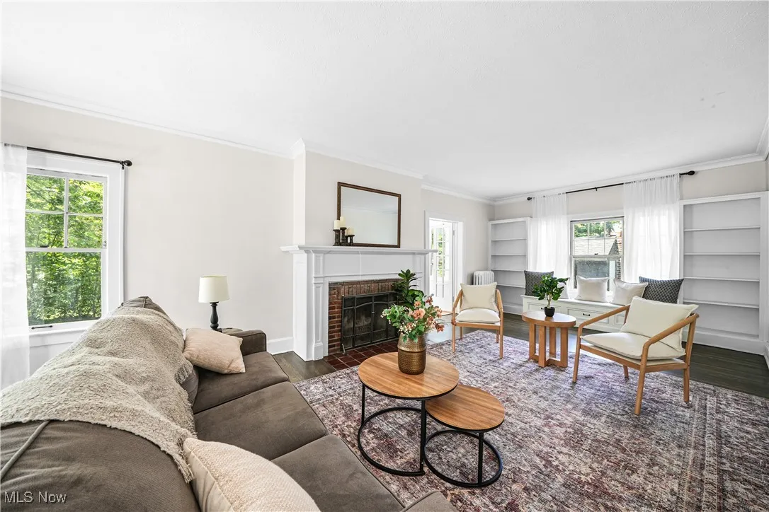 Living area featuring ornamental molding, a fireplace, wood finished floors, and built in features