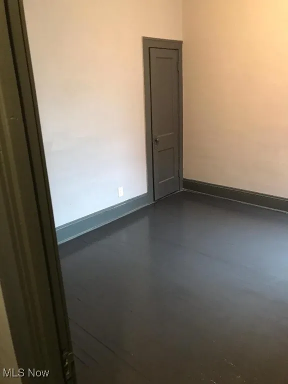 Empty room featuring concrete flooring and baseboards