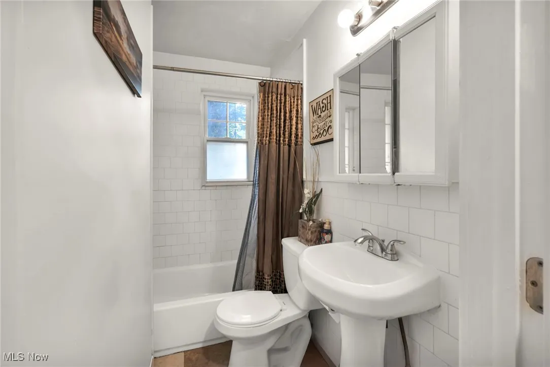 Full bath with tile walls, shower / bath combo, and backsplash
