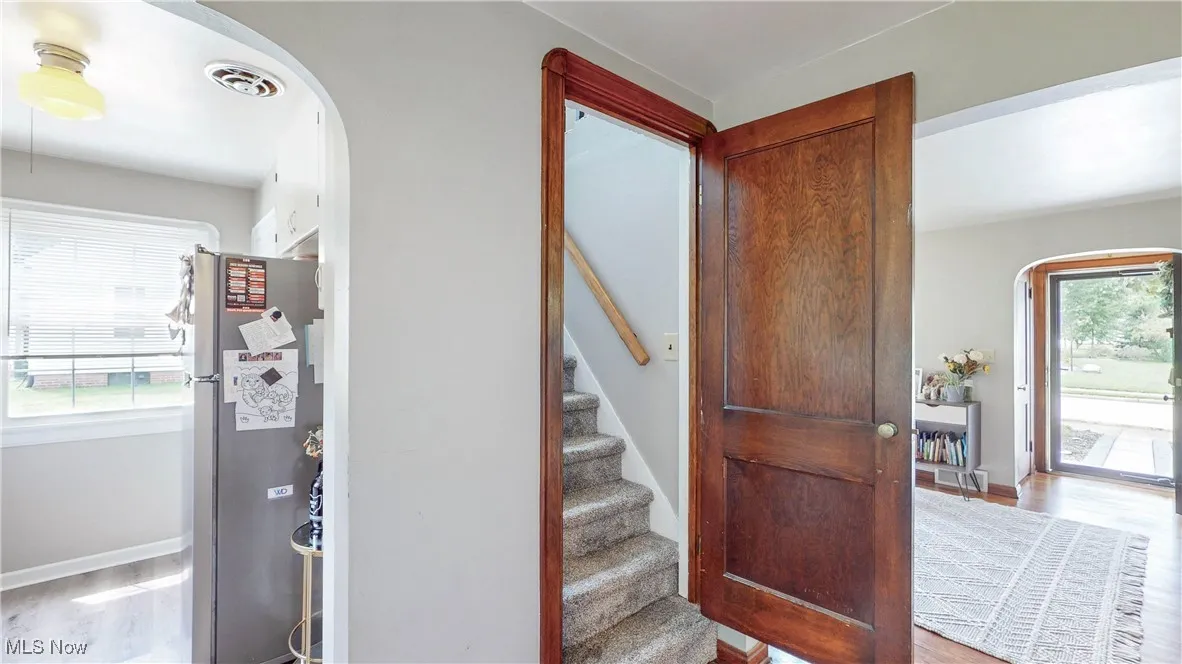 Entryway with arched walkways, wood finished floors, and stairway