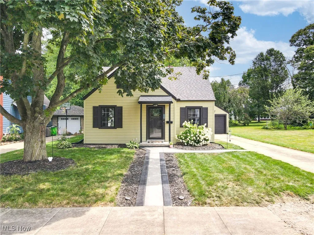 Bungalow-style house with a garage, a front yard, a shingled roof, and driveway