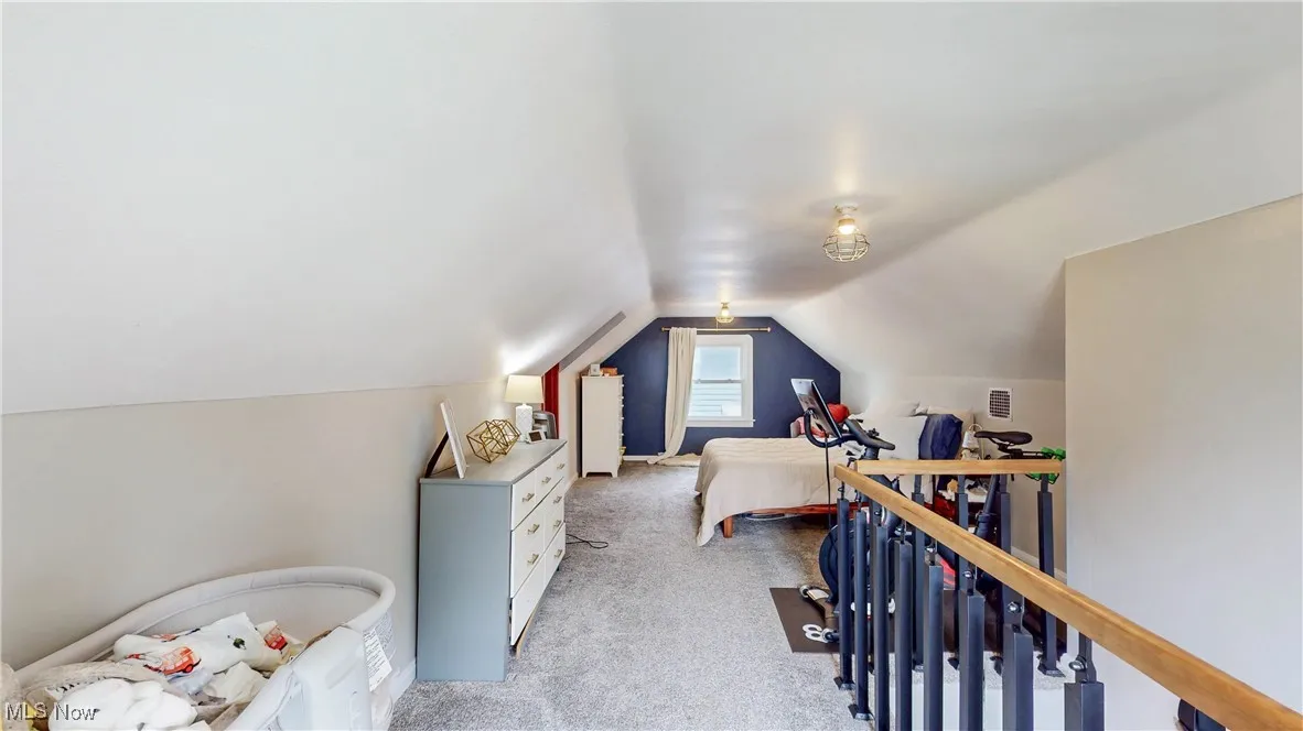 Bedroom with light carpet and lofted ceiling