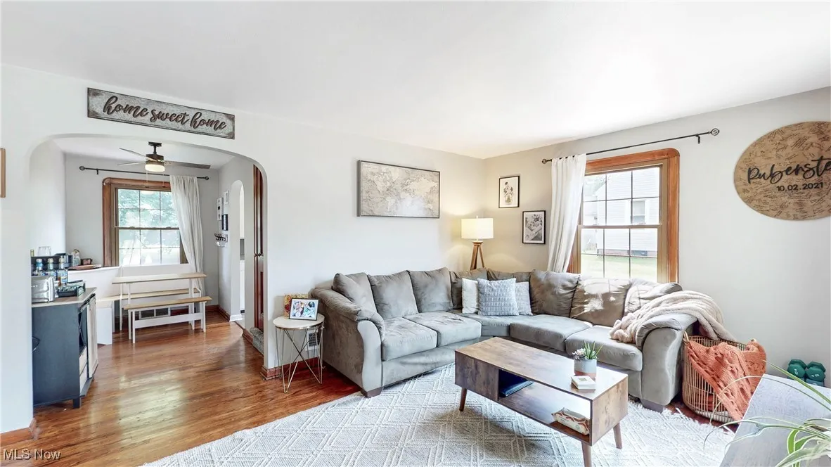 Living room featuring wood finished floors, ceiling fan, and arched walkways
