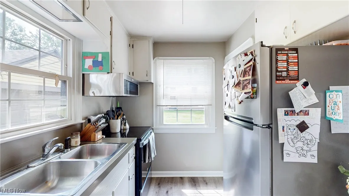 Kitchen with stainless steel appliances, white cabinetry, and light wood finished floors