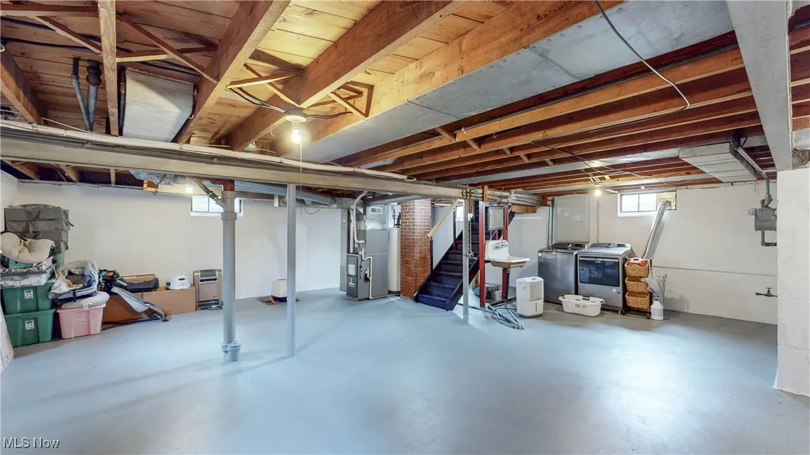 Basement with washer and clothes dryer, stairway, and heating unit