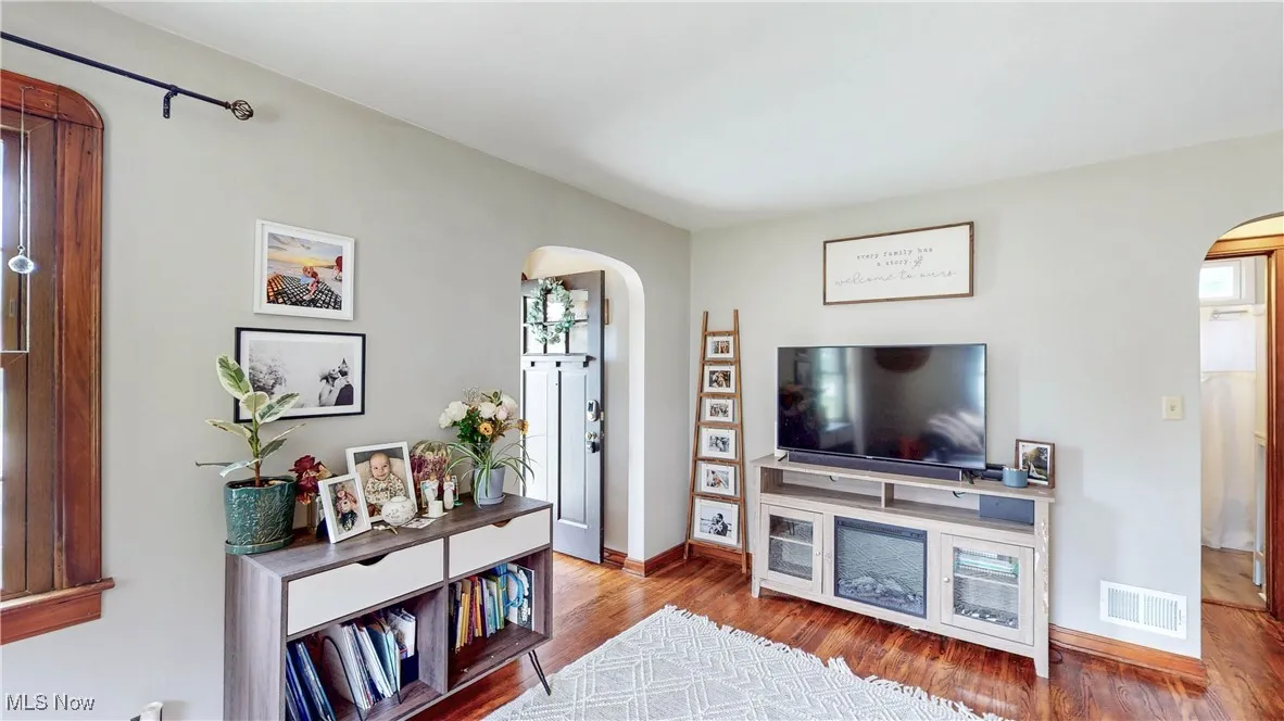 Living area featuring arched walkways and wood finished floors