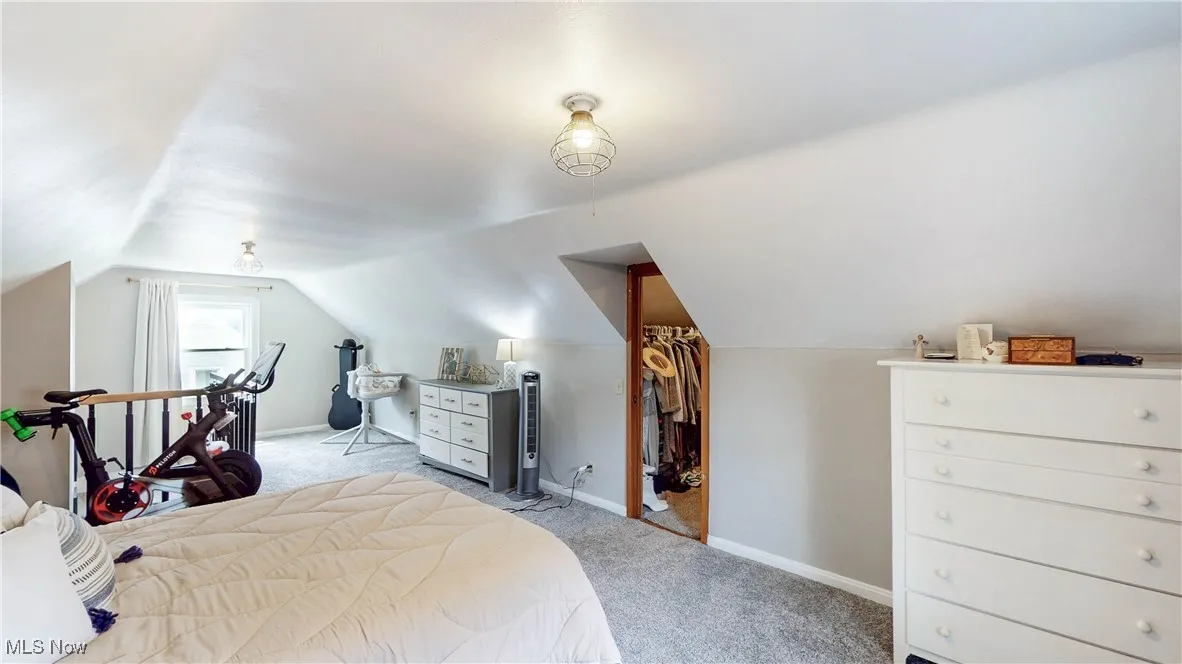 Bedroom with light carpet and vaulted ceiling