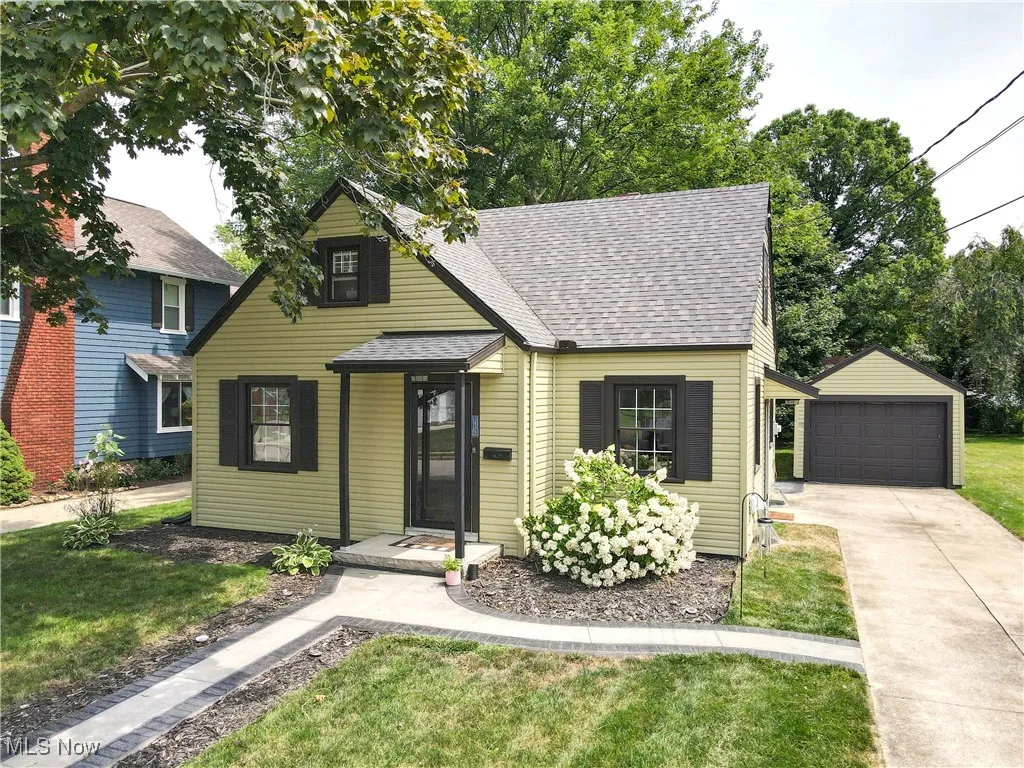 View of front of property featuring roof with shingles, an outbuilding, a front yard, and a detached garage