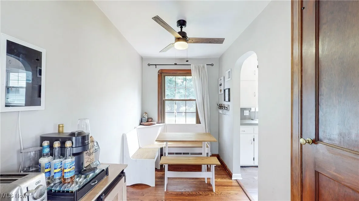Dining space with wood finished floors, arched walkways, and ceiling fan