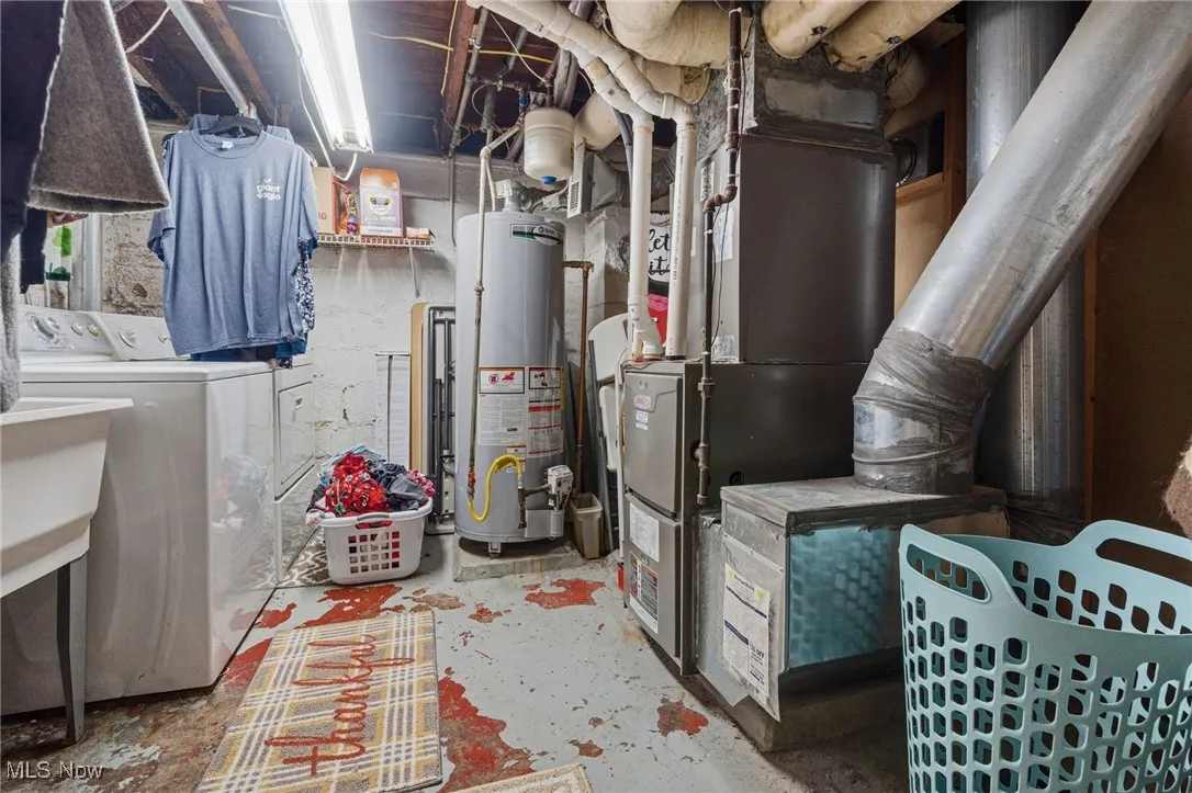 Utilities featuring washer and clothes dryer, water heater, and heating unit