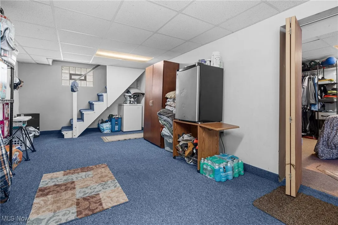 Below grade area featuring a drop ceiling, carpet flooring, and stairway