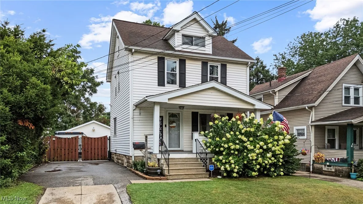 Traditional style home with covered porch, a gate, a front lawn, and roof with shingles
