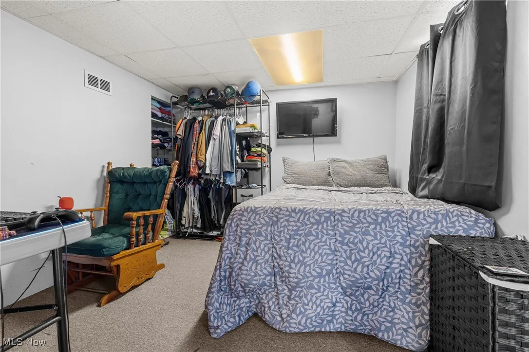 Carpeted bedroom with a paneled ceiling and a closet