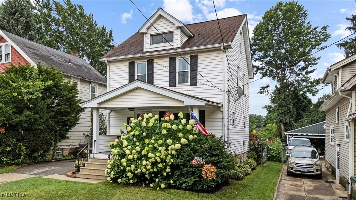 Traditional style home with covered porch, roof with shingles, and a front lawn