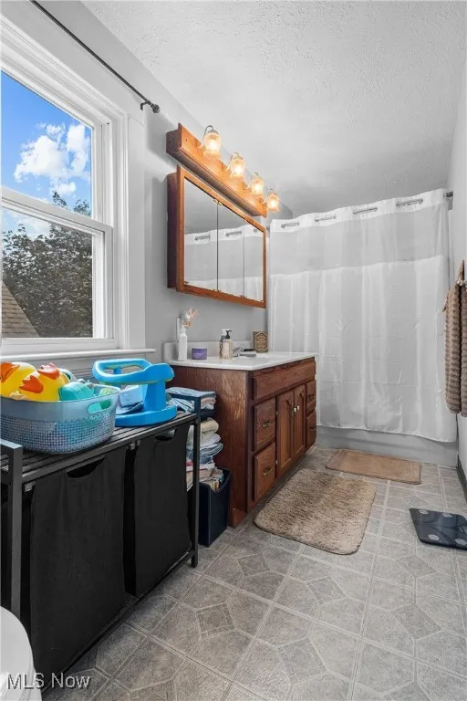 Full bath with vanity, a textured ceiling, and a shower with curtain