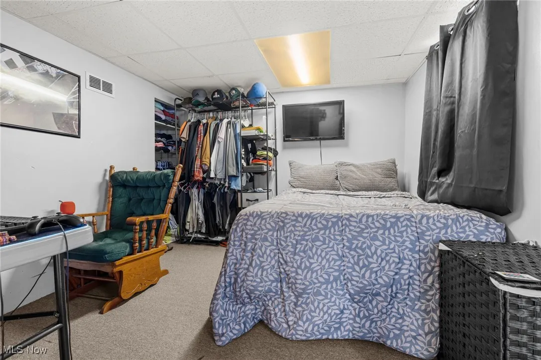 Bedroom with a drop ceiling, carpet, and a closet