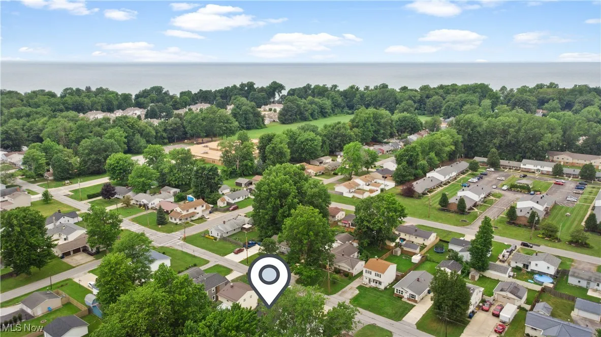 Aerial perspective of suburban area with a nearby body of water and a tree filled landscape