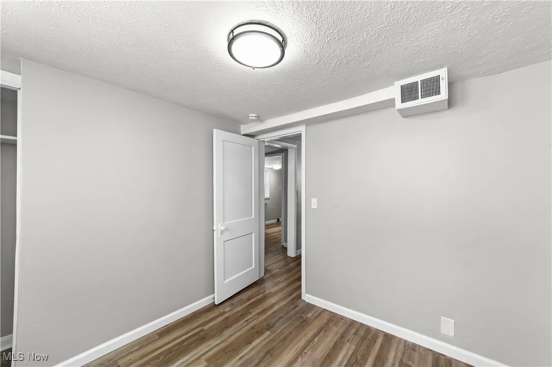 Unfurnished bedroom with wood finished floors, a closet, and a textured ceiling