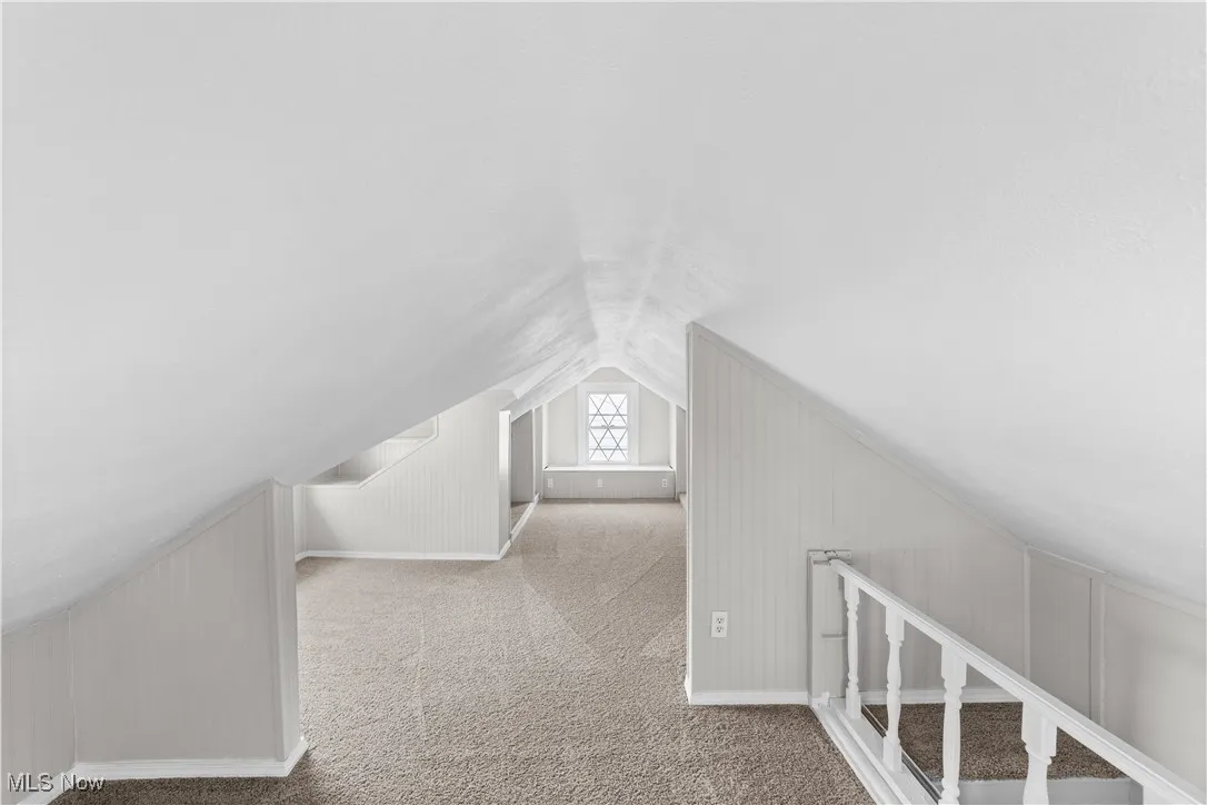 Bonus room featuring lofted ceiling, carpet flooring, and a decorative wall