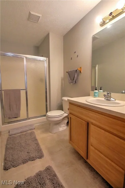 Full bathroom featuring vanity, a shower stall, and a textured ceiling