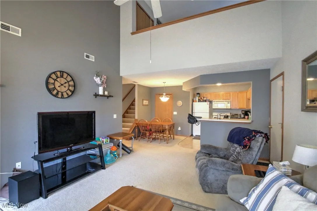Living room with carpet, a towering ceiling, and stairs
