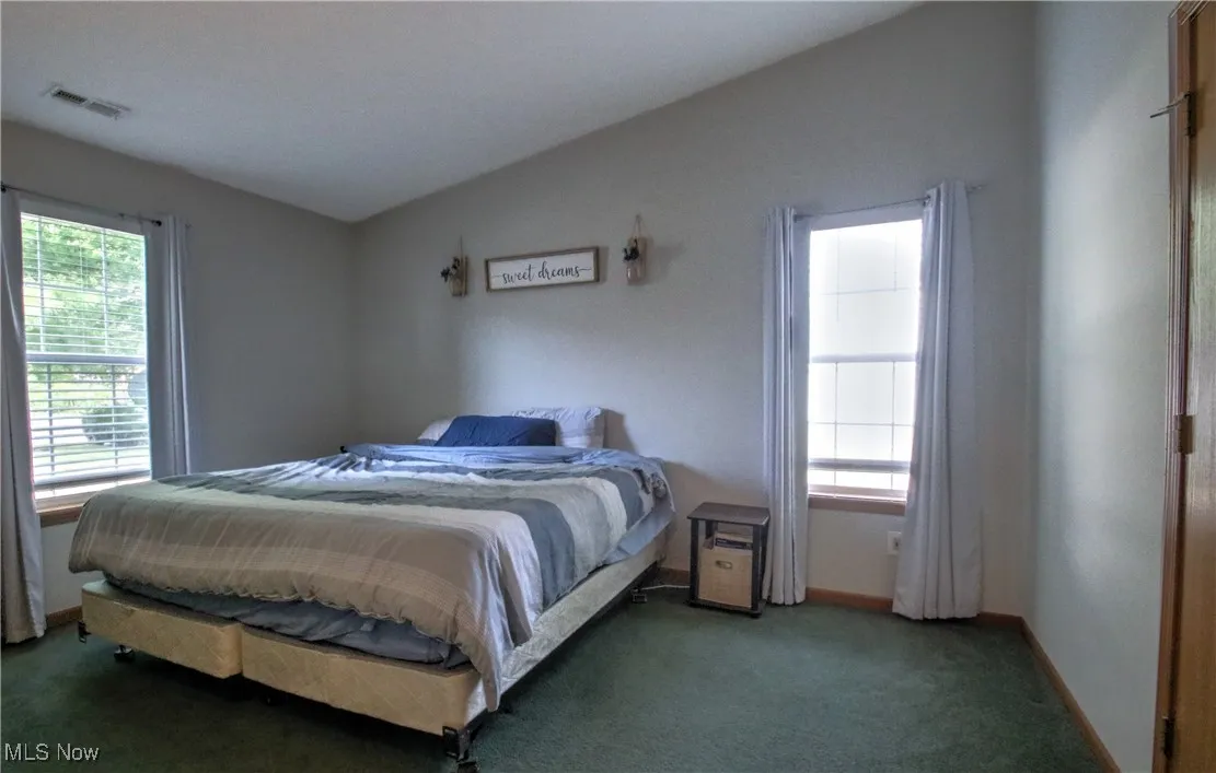 Carpeted bedroom featuring lofted ceiling and baseboards