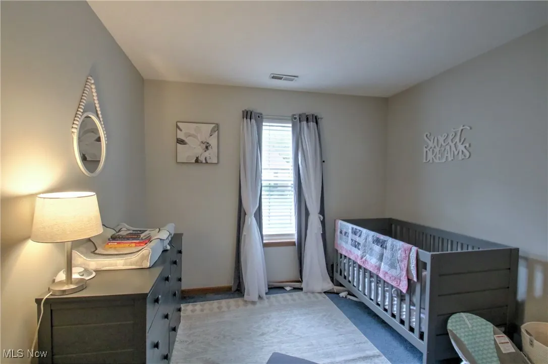 Bedroom with a nursery area and carpet flooring