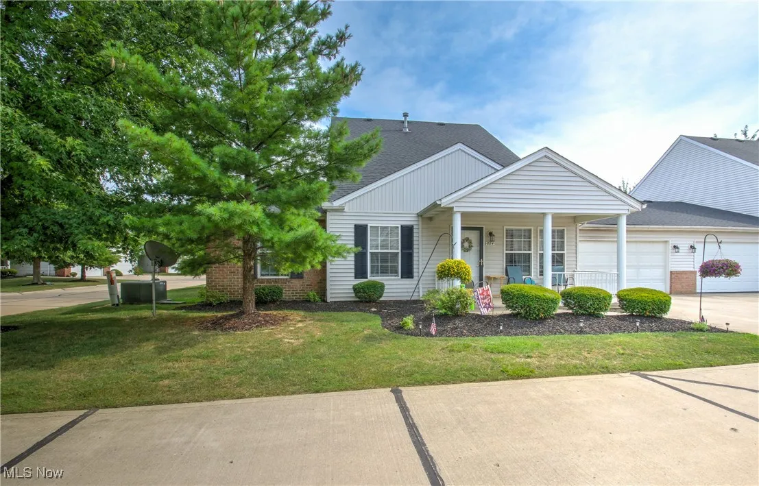 View of front of property with a front yard, a garage, concrete driveway, a porch, and a shingled roof